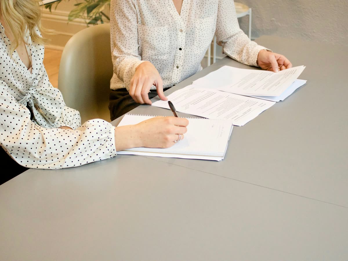 Duas pessoas revisando documentos em uma mesa de atendimento